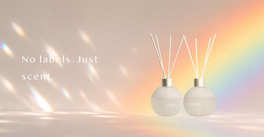 Two AIRY® Fragrances reed diffusers in identical frosted glass bottles against a soft rainbow light background, representing genderless home fragrance designed for every person, AIRY® Fragrances .