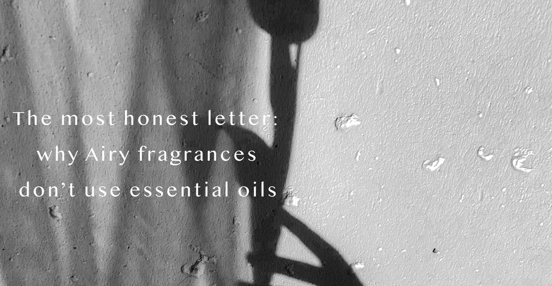 A minimalist black-and-white image of a shadow on a textured wall, accompanying an editorial letter explaining Airy Fragrances' intentional use of aroma chemicals over essential oils for balance and scent precision.
