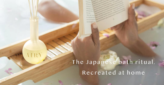 AIRY Forest Breath 森 alcohol-free reed diffuser placed on a bamboo bath tray beside fresh flowers and a book, evoking a Japanese ofuro bath ritual at home,  luxury home fragrance by AIRY Fragrances.