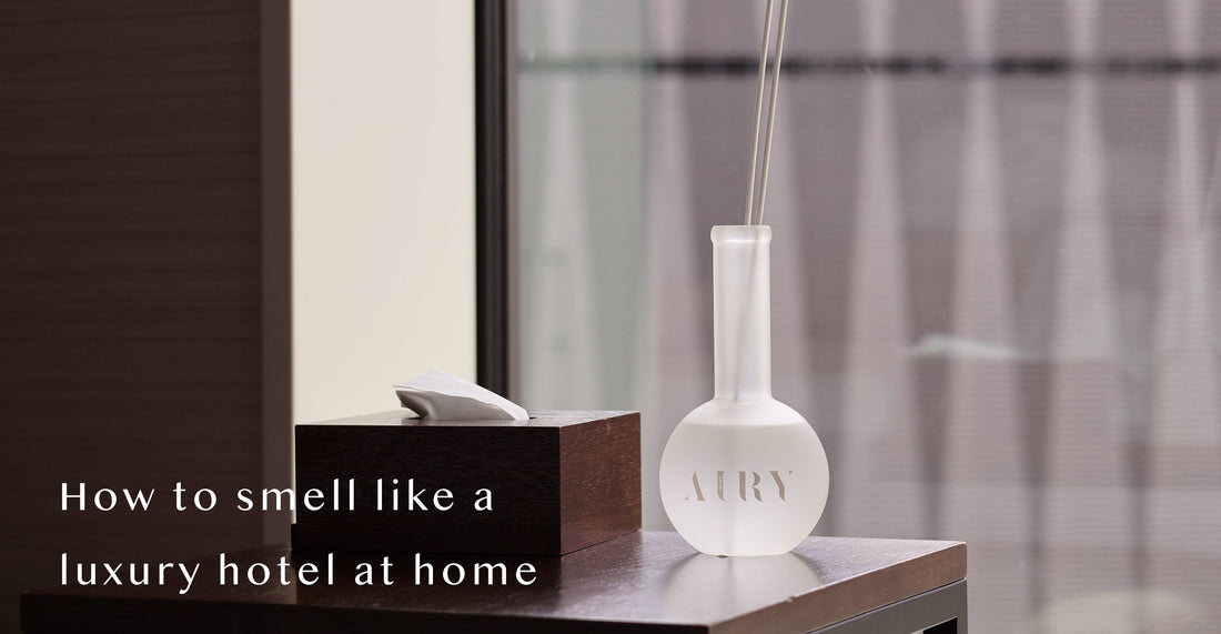 AIRY® Fragrances reed diffuser on a dark wooden bedside table in a minimal hotel-style room with sheer curtains and warm light,  luxury Japanese home fragrance by AIRY® Fragrances.