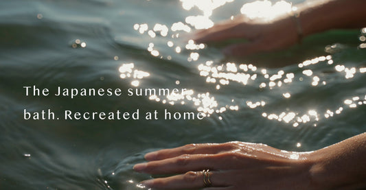 Hands resting in sunlit water with light reflecting off the surface, evoking the stillness and warmth of a Japanese summer rotenburo open-air bath experience,  AIRY® Fragrances.