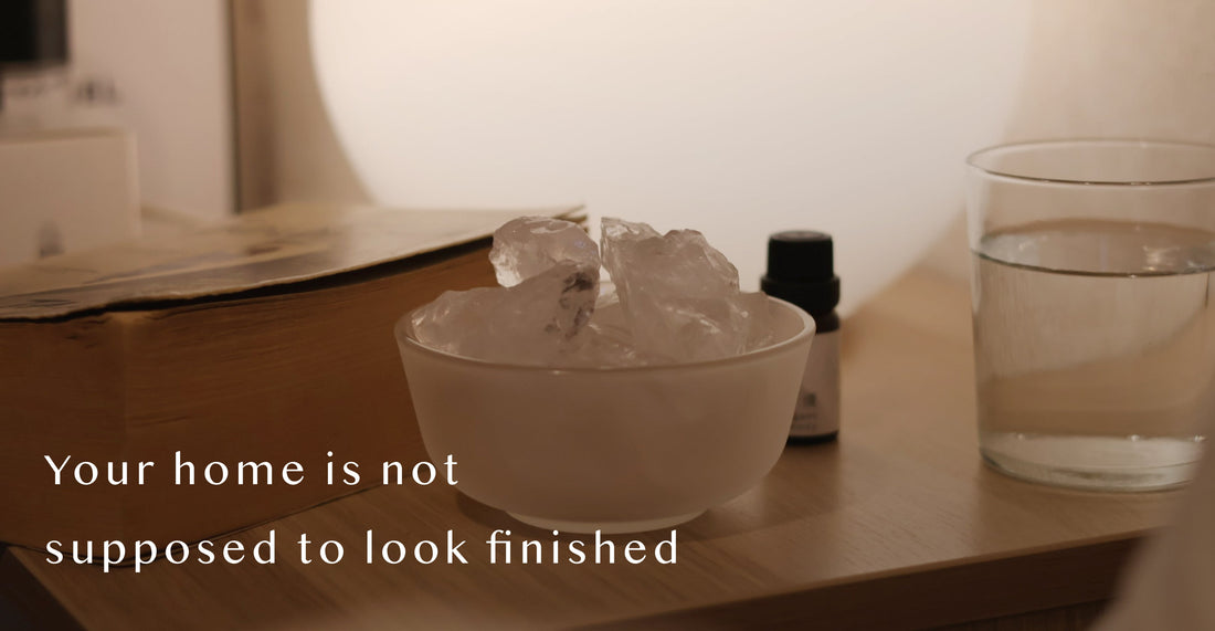 AIRY® Fragrances clear quartz crystal stone diffuser in a raw ceramic bowl on a wooden surface, styled with a glass of water and fragrance oil bottle in warm low light,  wabi-sabi inspired home fragrance by AIRY® Fragrances. 