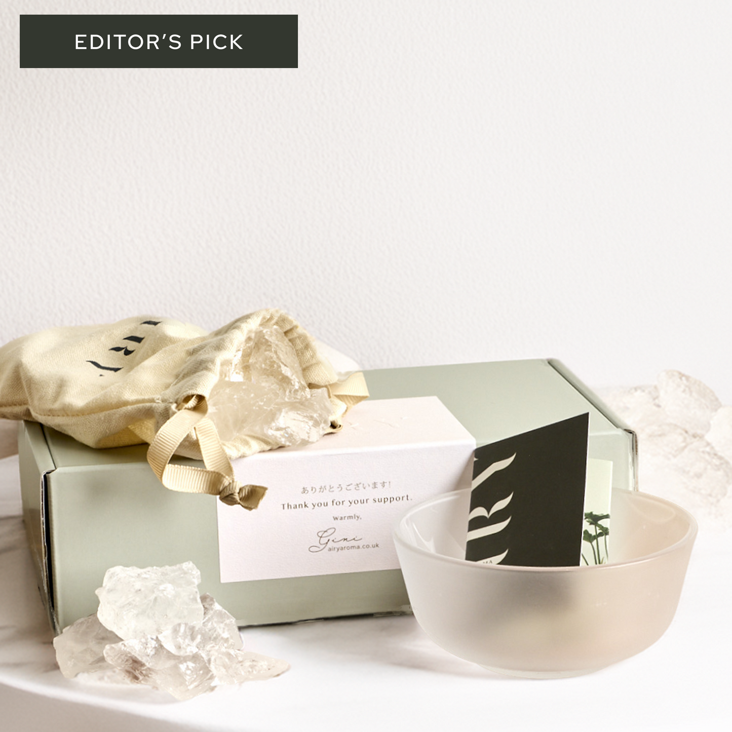 Airy Fragrances luxury Stone Diffuser Set, an Editor’s Pick featured in The Guardian and Ideal Home. Image shows the complete minimalist unboxing experience: a frosted round glass container, 500g of raw natural Clear Quartz stones in a signature cotton drawstring bag, and premium gift packaging. 100% natural Japanese-crafted wellness set for mental clarity and minimalist home decor