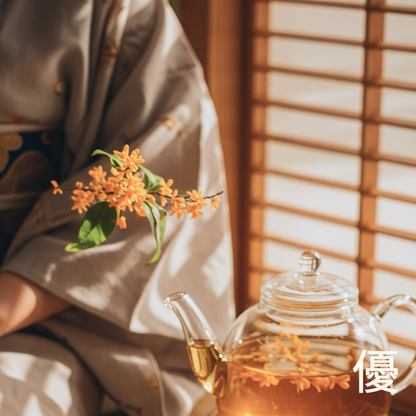 Kyoto-inspired lifestyle ritual for Elegant Harmony 優: A woman in a traditional kimono holding golden osmanthus blossoms next to a glass teapot of white tea. This visual story highlights the sophisticated scent notes of Kyoto Osmanthus and White Tea.
